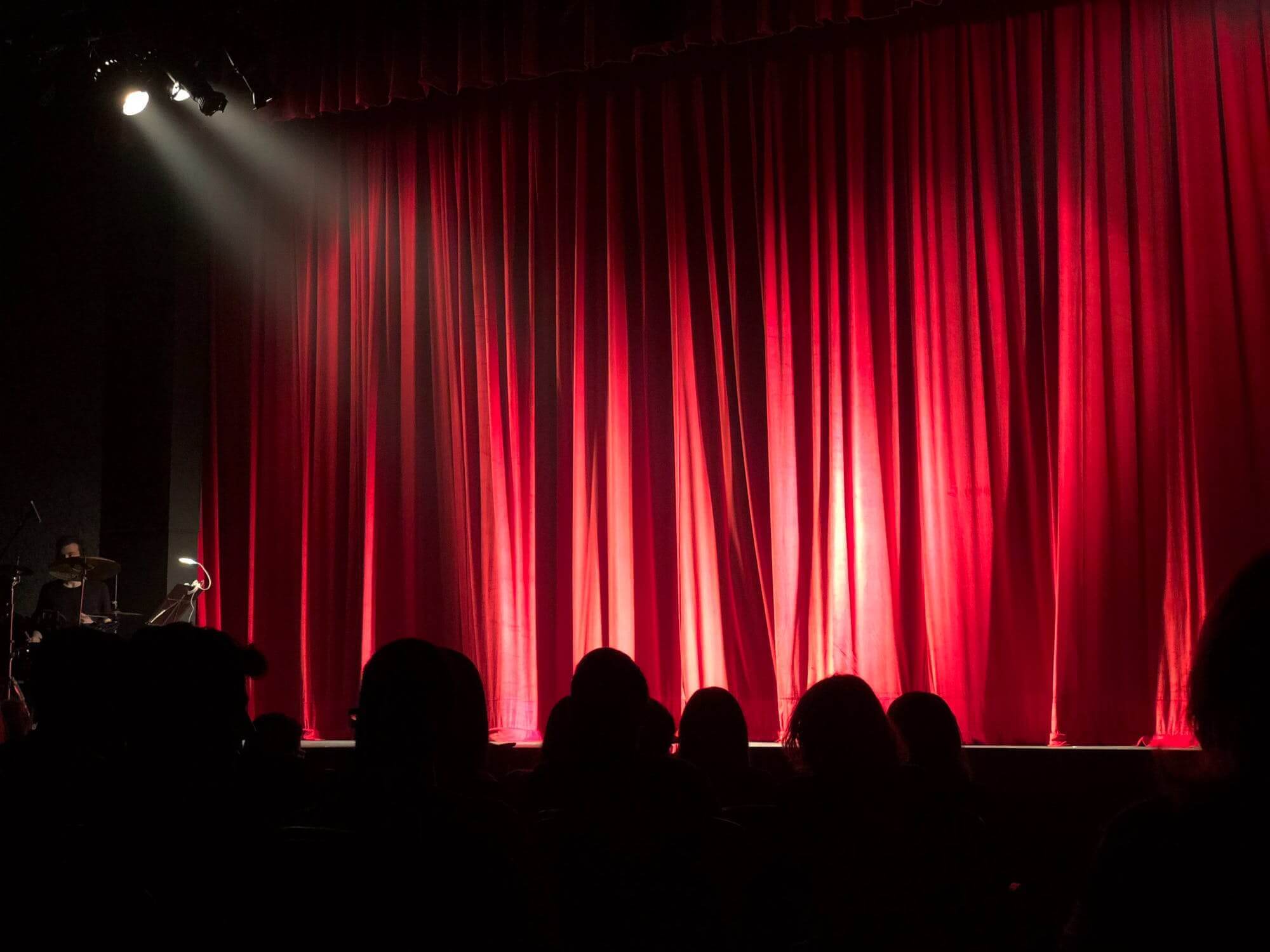 audience looking at stage with closed curtains