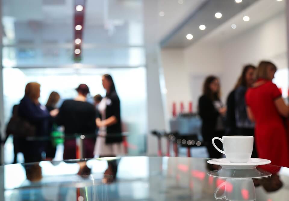 coffee cup in the foreground, event attendees in the background out of focus