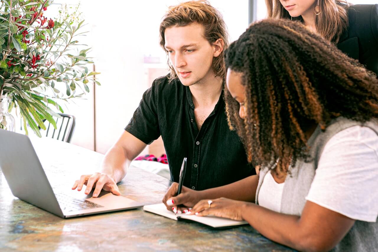 group of people looking at laptop and writing notes