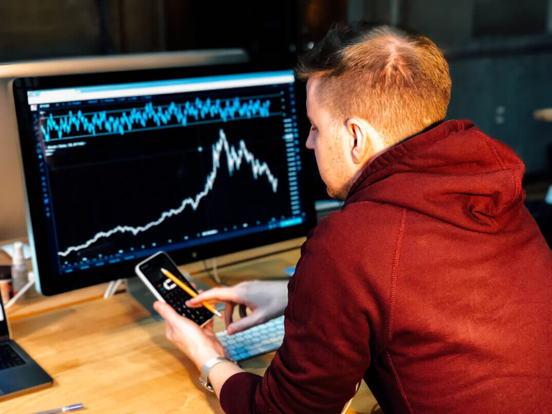 man tapping phone in front chart on computer