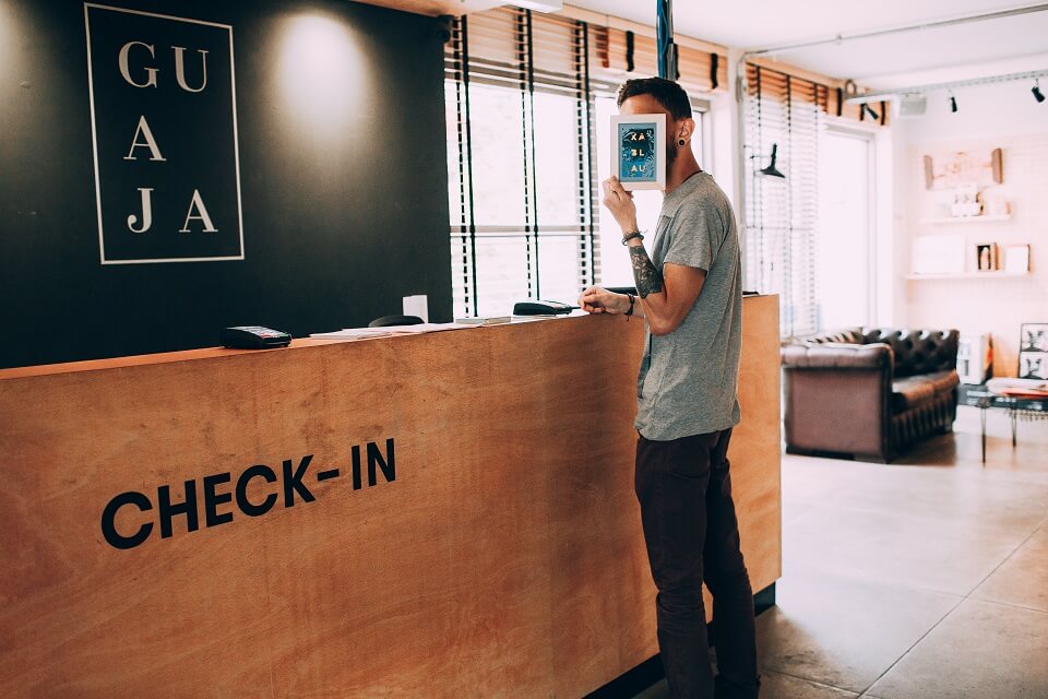 man standing in front of hotel check-in desk, covering face