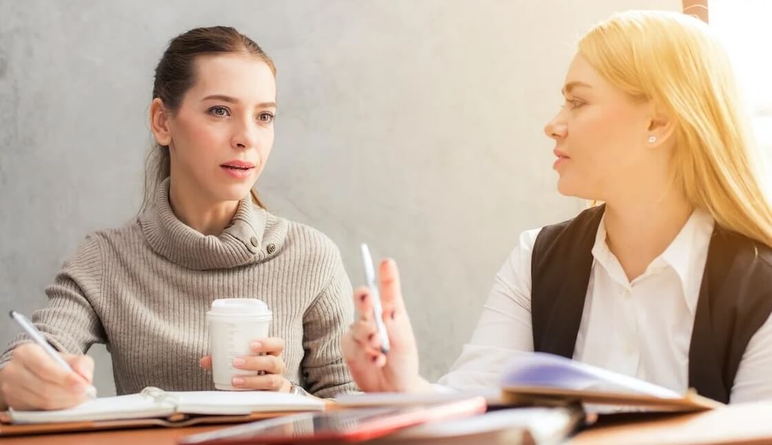 two women discussing survey questions to ask attendees