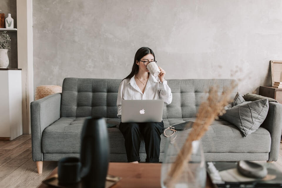 woman working on laptop while drinking from mug