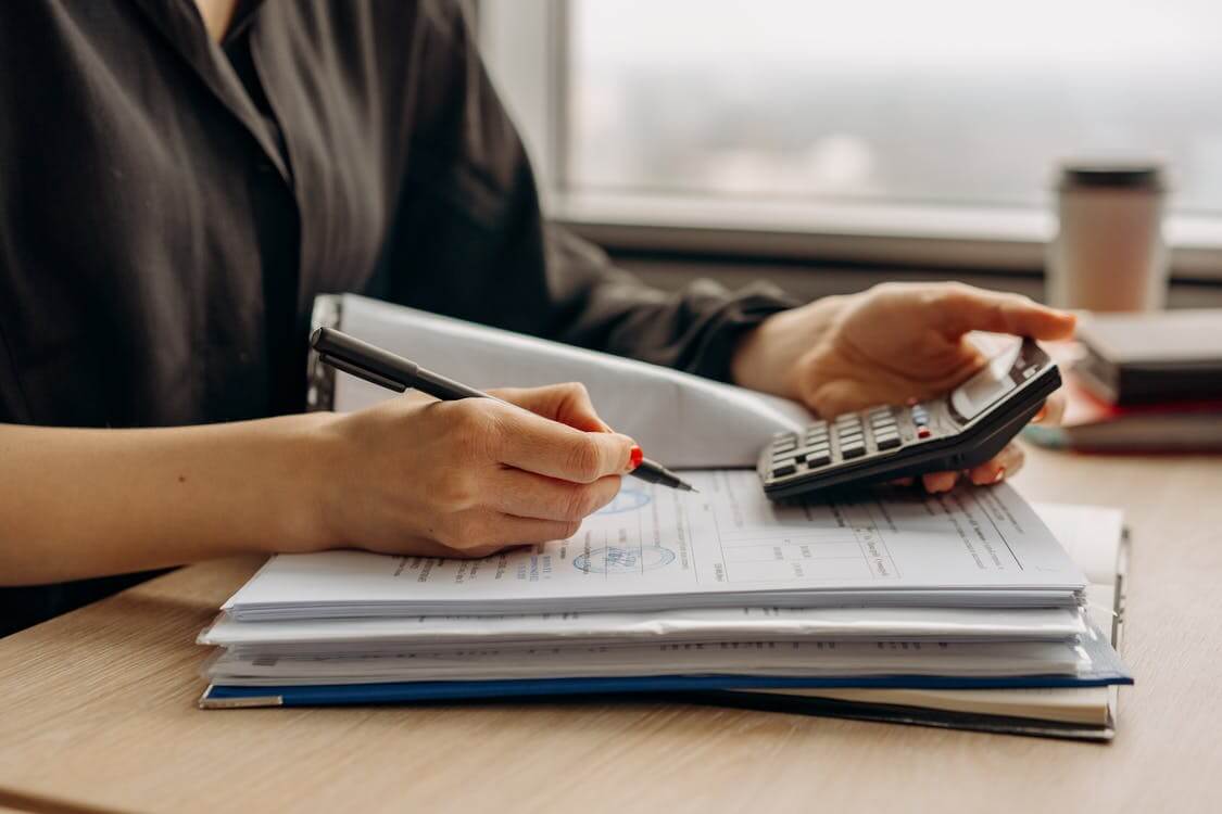 woman writing and using calculator